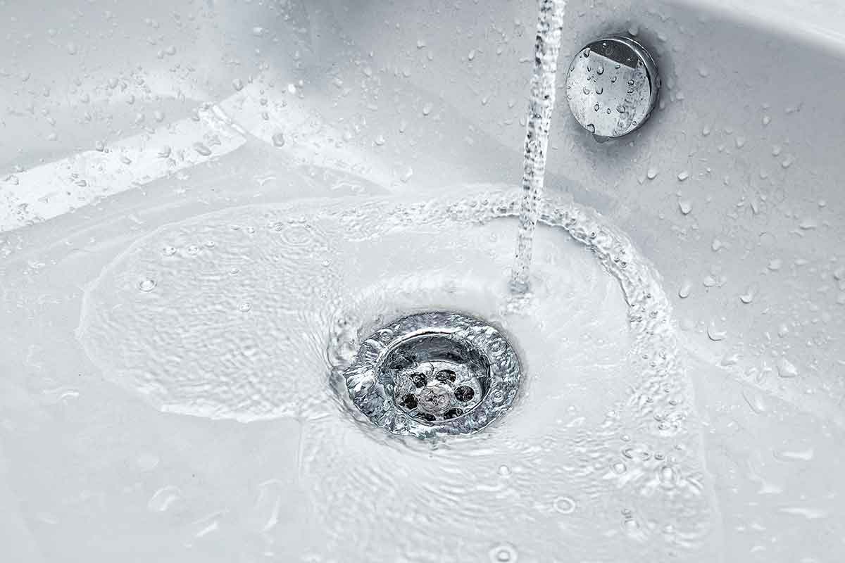 Wasted clean tap water draining into a sink